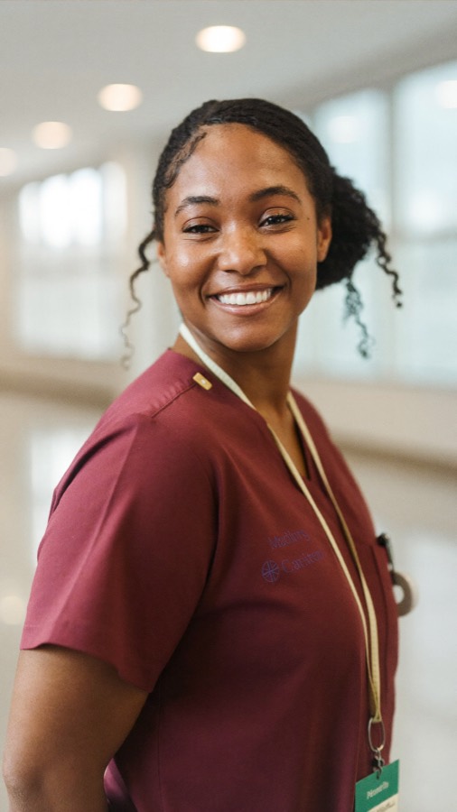 A nurse in scrubs smiling at the camera